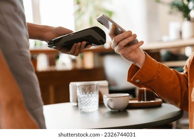 Close up young man paying in cafe with mobile phone using contactless bank terminal - Powered by Shutterstock