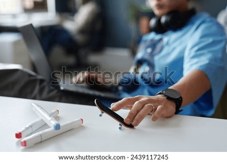 Close up of young man playing with fingerboard on table at office workplace