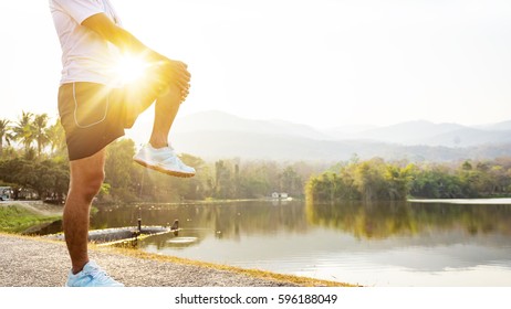 close up young man runner warm up and stretching before training at sunset time