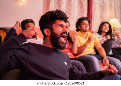 Close up of young man shouting and cheering for his team support while watching sports on tv from home with his friends.