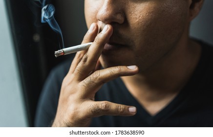 Close up young man smoking a cigarette darknest mood and tone. - Shutterstock ID 1783638590