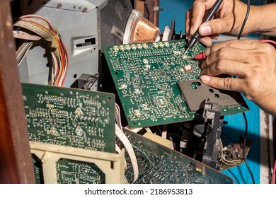 Close Up Of Young Man Technician Repairing A Television. Repairman Are Checking Television Circuit Board With Multimeter. TV Repair Service Center Concept