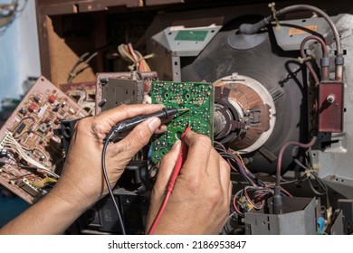 Close Up Of Young Man Technician Repairing A Television. Repairman Are Checking Television Circuit Board With Multimeter. TV Repair Service Center Concept