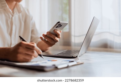 Close up of young man using calculator and laptop for doing financial mathematics on wooden table in office and working background - business, tax, accounting, statistics and analytical research conce