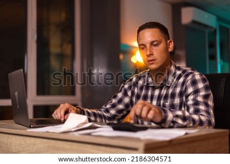 Close up young man using calculator, managing household monthly budget, summarizing taxes or bills, planning future investments, doing financial affairs at home, accounting bookkeeping concept.