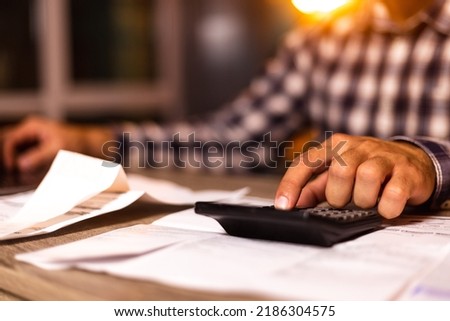 Close up young man using calculator, managing household monthly budget, summarizing taxes or bills, planning future investments, doing financial affairs at home, accounting bookkeeping concept.