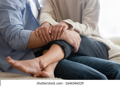 Close up of young man and woman sit on couch at home hugging enjoying romance in living room, loving couple embrace and cuddle having tender intimate moment, show affection and care in relationships