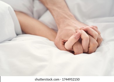 Close up of a young married couple holding hands during the moment of intimacy in bed - Powered by Shutterstock