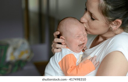 Close Up Of Young Mother Holding Her Crying Baby Daughter, Kissing Her