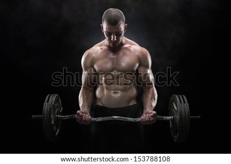 Close up of young muscular man lifting weights over dark background
