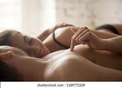 Close up young newlyweds naked couple in love lying in bed in the morning. Smiling happy wife touch satisfied husband wake up together after passionate night at home Romantic relationships, sex concep