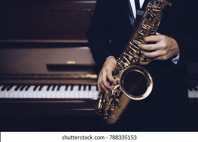close up of Young Saxophone Player hands  playing alto sax musical instrument over the piano  background,  closeup with copy space, vintage tone,  can be used for music background - Shutterstock ID 788335153