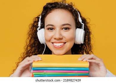 Close Up Young Smiling Black Teen Girl Student She Wear Casual Clothes Headphones Hold Books Listen Music Radio Lecture Isolated On Plain Yellow Color Background High School University College Concept