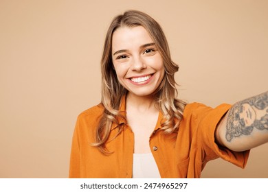 Close up young smiling happy woman she wear orange shirt casual clothes doing selfie shot pov on mobile cell phone isolated on plain pastel light beige background studio portrait. Lifestyle concept - Powered by Shutterstock