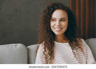 Close up young smiling satisfied minded woman wear casual clothes sits on grey sofa couch looking aside stay at home hotel flat rest relax spend free spare time in living room indoor. Lounge concept - Shutterstock ID 2367234573