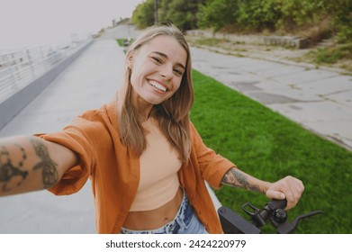 Close up young smiling woman wear orange shirt casual clothes sit on e-scooter do selfie shot pov on mobile cell phone walk rest relax in spring city park outdoors on nature. Urban lifestyle concept - Powered by Shutterstock