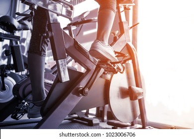 Close up young sport woman exercising on bicycle workout at fitness gym