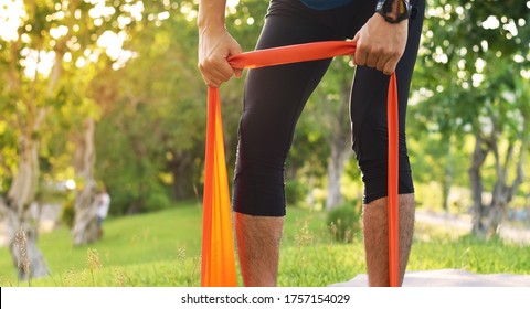 Close Up Of Young Sports Man Do Exercise With Elastic Band In The Park, Dead Lift Workout, Healthy Lifestyle