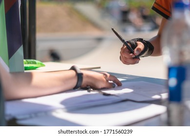 Close up of young teenager signing up for skateboarding competition outdoors. Hand with wrist splint filling up registration form for extreme sport competition - Powered by Shutterstock