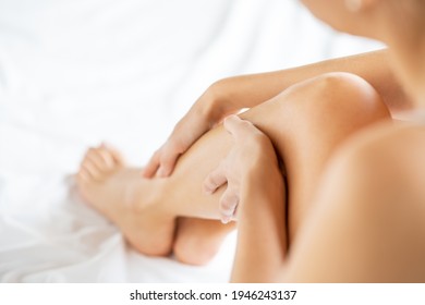 Close up of young woman applying moisturizer on legs. Back view of beauty woman massaging her legs with perfect smooth soft skin at home. Epilation, beauty and health concept.