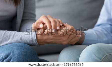 Close up young woman covering hands of mature senior mother, asking for forgiveness, feeling guilty, apologizing indoors. Compassionate grownup daughter comforting supporting retired mum at home.