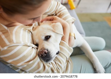 Close up of young woman cuddling with white Labrador dog at home, copy space - Powered by Shutterstock