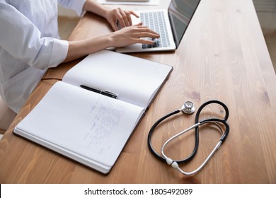 Close Up Young Woman Doctor Working On Laptop In Hospital, Sitting At Table, Female Therapist Physician Gp Work Desk With Stethoscope And Medical Documents, Patient Card, Illness History