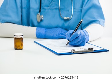 Close Up Of Young Woman Doctor Working At Her Desk In Hospital,General Practitioner Sitting In Office Writing Prescription Medicine Script,female Therapist Physician Filling Patient Medical Documents