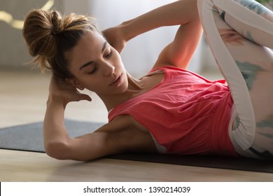 Close up young woman doing crisscross exercise for abs lying on sports mat indoors, girl wearing sportswear makes bicycle crunches fitness working out at home, healthy active lifestyle routine concept - Shutterstock ID 1390214039