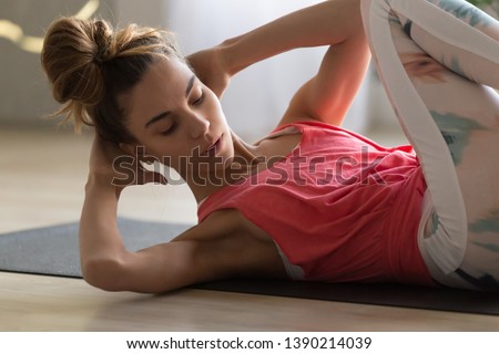 Close up young woman doing crisscross exercise for abs lying on sports mat indoors, girl wearing sportswear makes bicycle crunches fitness working out at home, healthy active lifestyle routine concept
