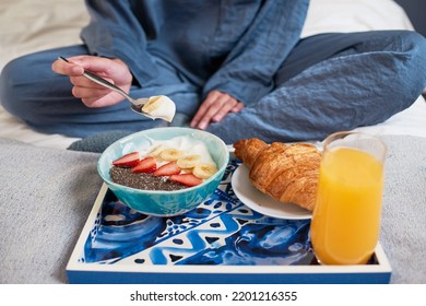 Close Up Of Young Woman Eating Breakfast Bowl In Bed In Pajamas