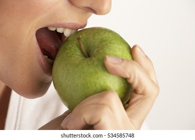 CLOSE UP OF YOUNG WOMAN EATING GREEN APPLE