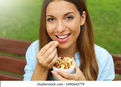 Close Up Of Young Woman Eating Mixed Nuts In The Park.