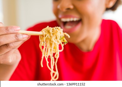 Close Up Of Young Woman Eating Noodles From Delivery Box Using Choopsticks