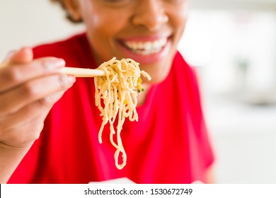 Close Up Of Young Woman Eating Noodles From Delivery Box Using Choopsticks