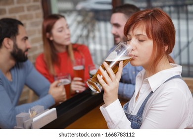 Close Up Of A Young Woman Enjoying Drinking Delicious Beer With Her Friends. Woman Sipping Craft Beer At The Pub