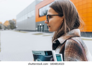Close up of a young woman in eyeglasses, teeth braces with notebooks, backpack smiling on college campus. Back to school. University, learning education concept. Copy space. Happy Student Life.