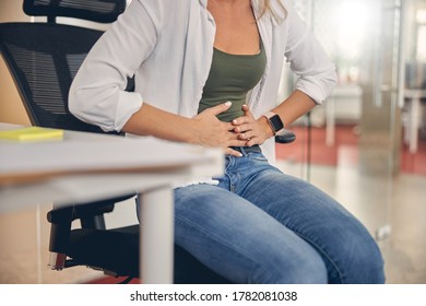 Close Up Of Young Woman Feeling Pain In Her Stomach While Sitting In Chair At Work