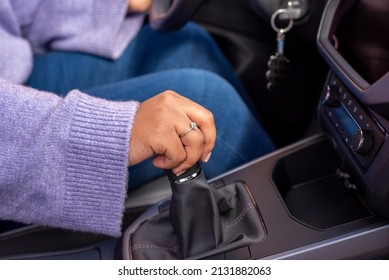 Close up Young woman hand on manual gear shift, shifting gearbox in car.Driver woman hand holding manual transmission or variable speed drive in car, shifting gear stick before driving car. 