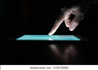 Close Up Of An Young Woman Hand Is Touching A Display Of A Lighted Screen Of Tablet Isolated On A Black Background