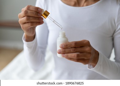 Close Up Young Woman Holding Bottle With Cosmetics Moisturizing Face Serum Or Oil, Facial Essence, Using Pipette, Cosmetology Beauty Routine Procedure At Home And Rejuvenation Skincare Concept