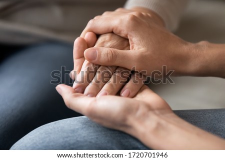 Close up young woman holding female hand of older mother, caring adult grown up daughter supporting and comforting mature mum, expressing love, two generations trusted relations