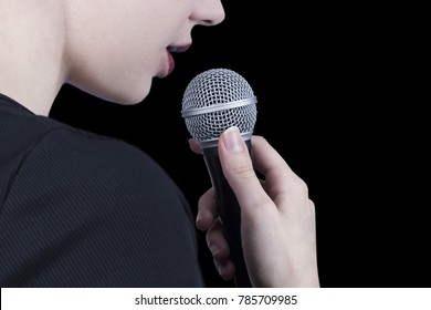 Close Up Of A Young Woman Holding Microphone And Singing With Black Background