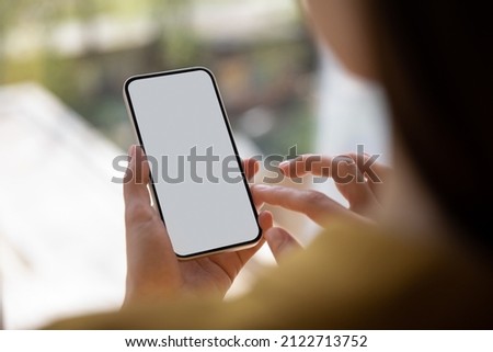 Close up young woman holding smartphone with blank mock up screen in hands, copy space for mobile software applications advertisement. female user playing games, web surfing or shopping online. Foto d'archivio © 