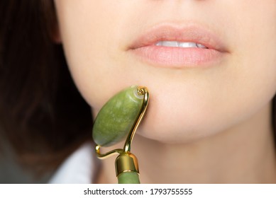 Close Up Of Young Woman With Jade Face Roller. She Is Doing Beauty Facial Massage Therapy