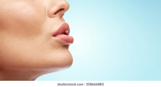 close up of young woman lips over blue