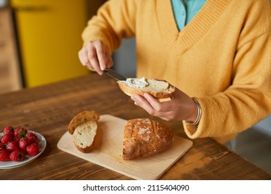 Close Up Of Young Woman Making Cheese Sandwich While Enjoying Breakfast In Kitchen, Copy Space