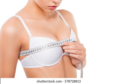 Close up of young woman measuring her bust size with tape measure.