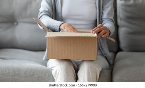 Close up of young woman open cardboard box order shopping online in Internet, female client or customer sit on sofa unwrap unpack delivery parcel buying things on web, good delivery concept - Shutterstock ID 1667279908