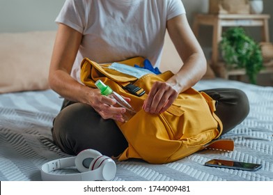 Close up of young woman packing her backpack with hand sanitizer. Prepairing for a travel after the end of quarantine. New life after Pandemic COVID-19 concept.